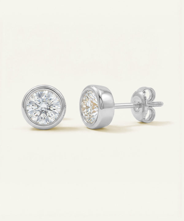 Pair of diamond stud earrings on a light beige background