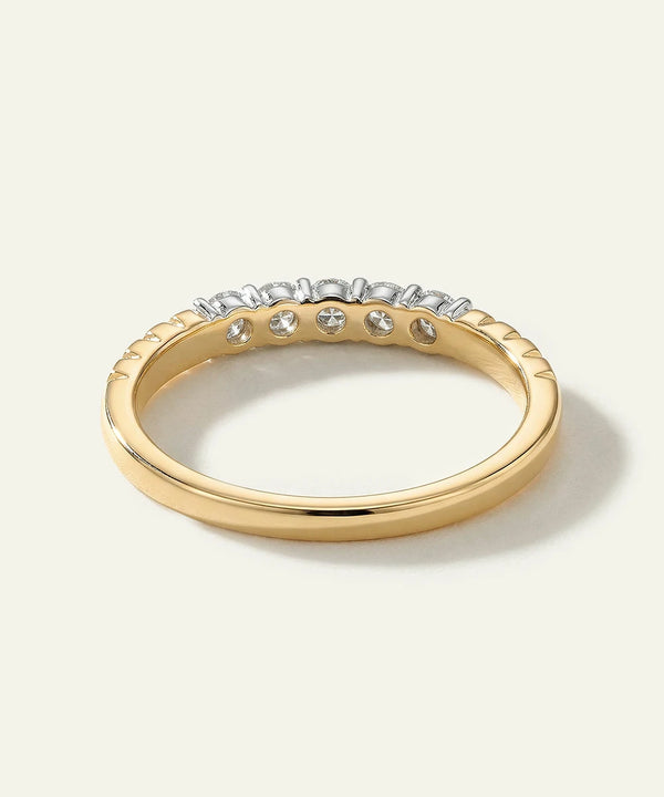 Gold ring with embedded diamonds on a light background