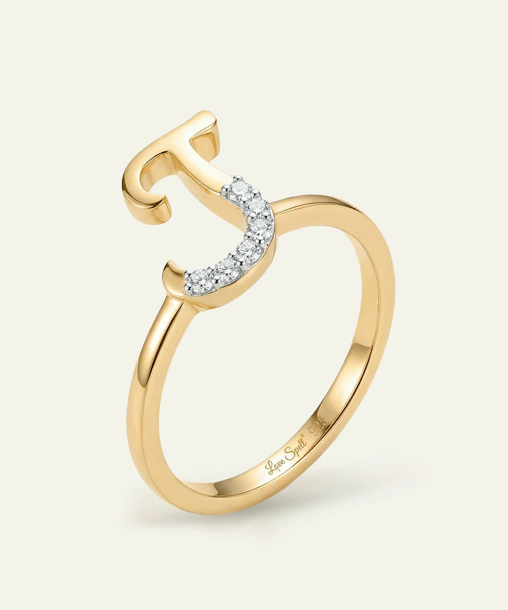 Gold ring with diamond accents on a light beige background