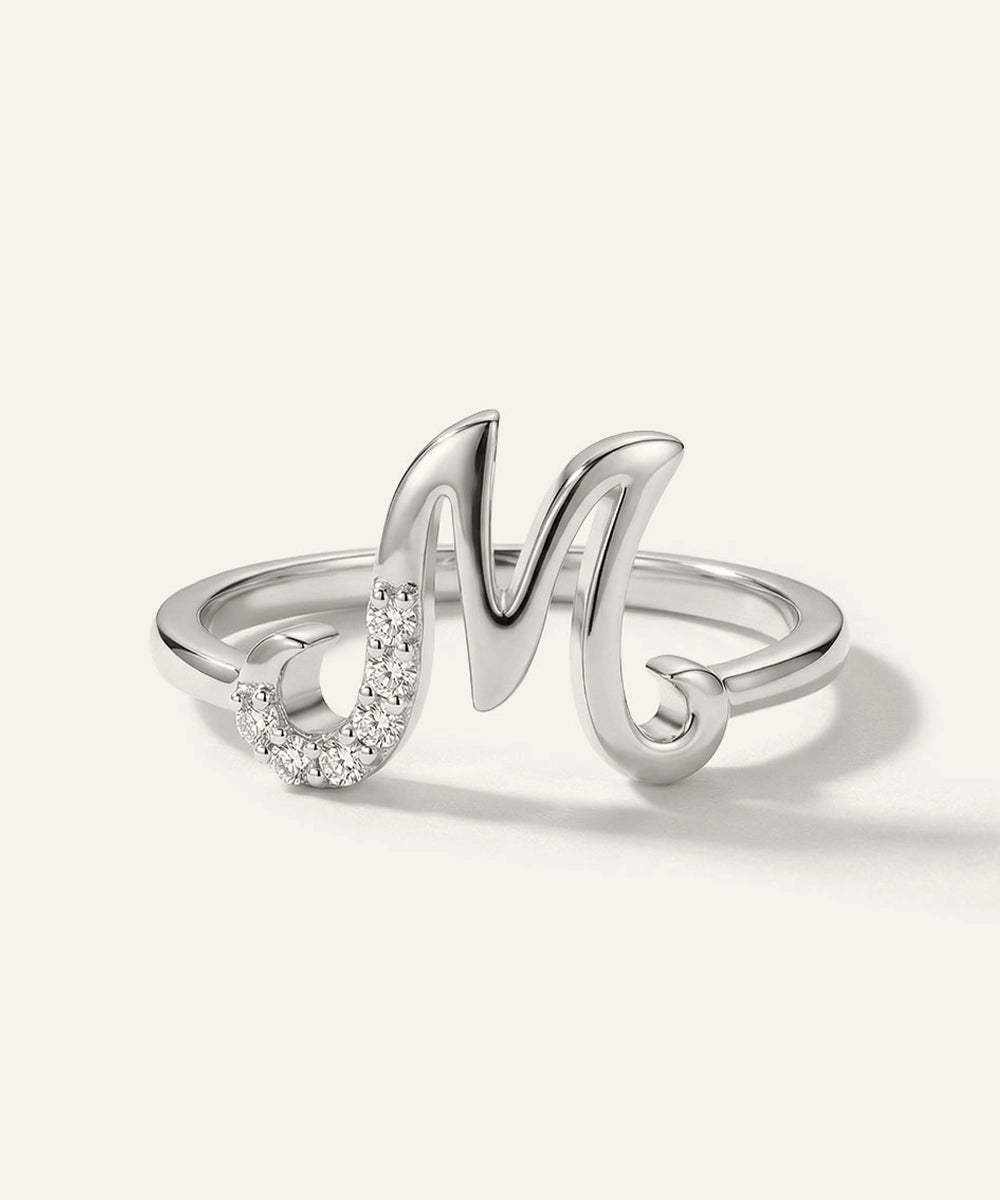 Silver ring with a letter 'M' design on a white background