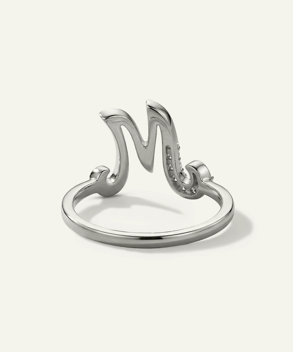 Silver ring with a stylized 'M' design on a white background