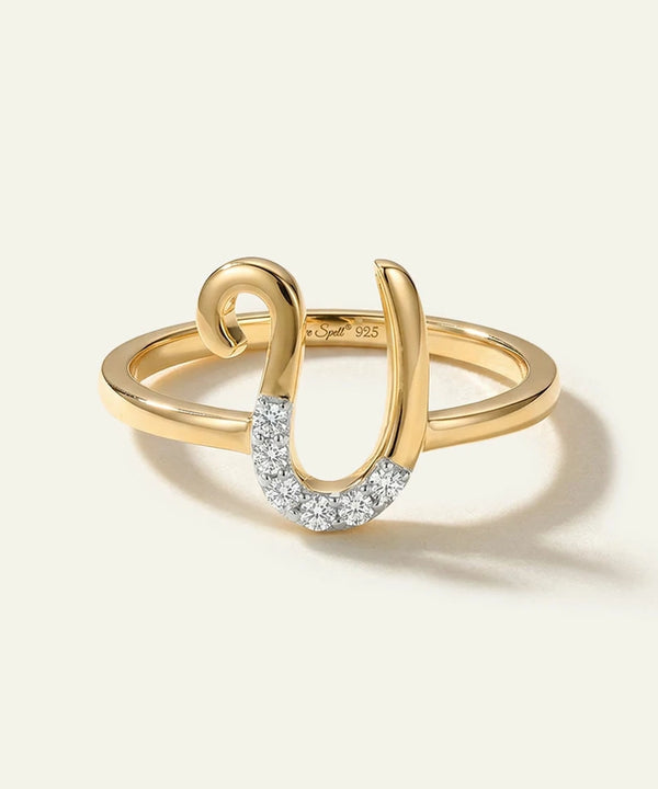 Gold ring with a horseshoe design and embedded diamonds on a white background