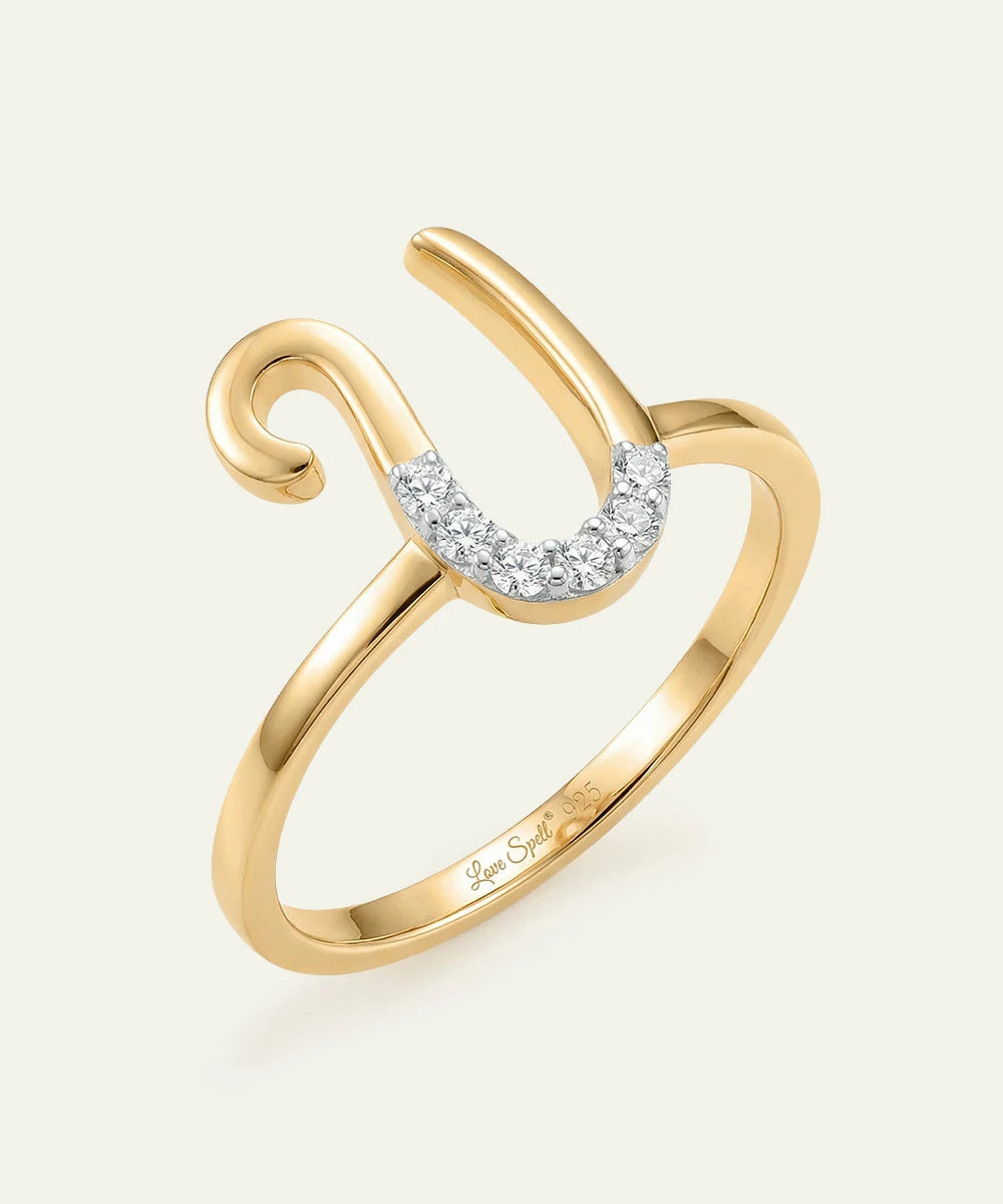 Gold ring with diamond accents on a light beige background