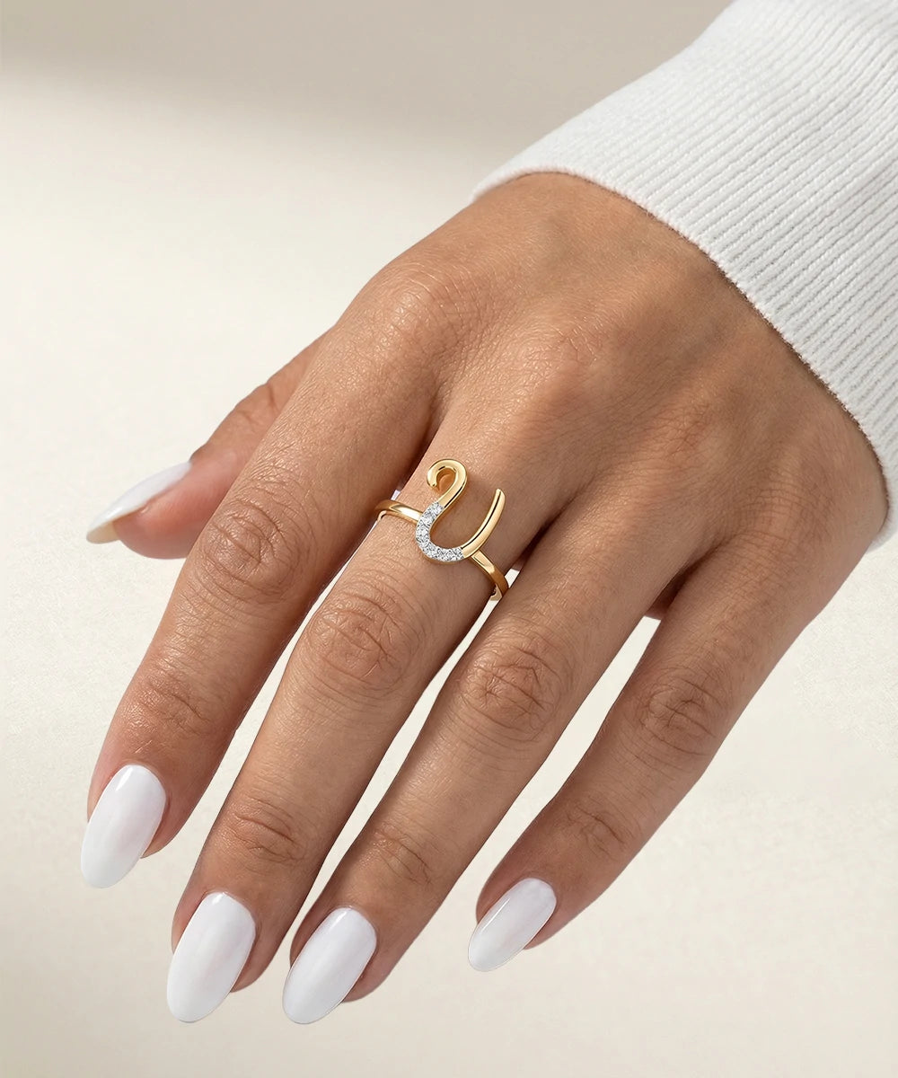 Hand wearing a gold ring with a diamond on a beige background