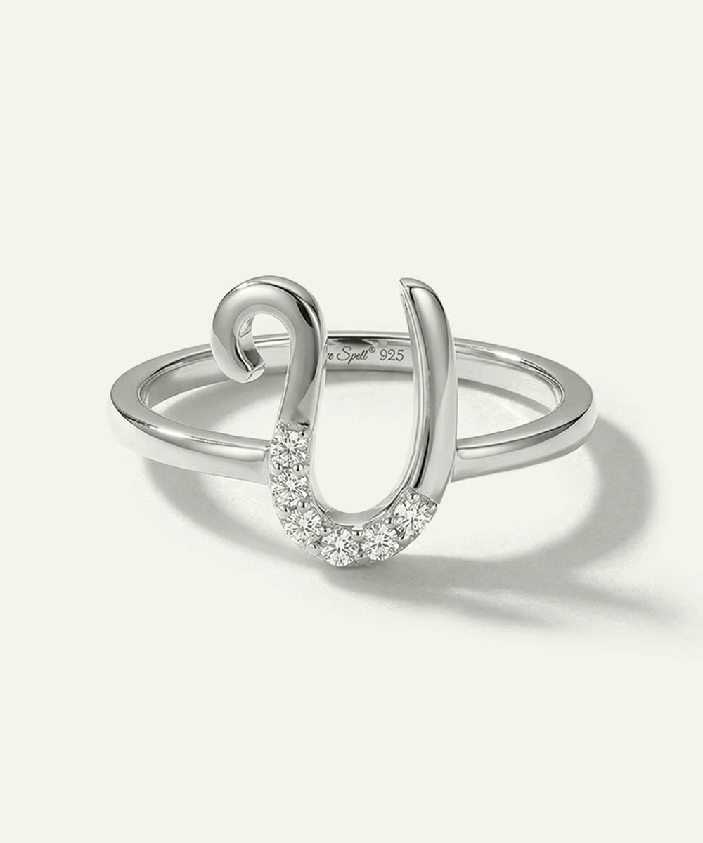 Silver ring with a horseshoe design and embedded stones on a white background