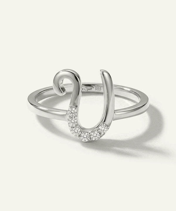 Silver ring with a horseshoe design and embedded stones on a white background
