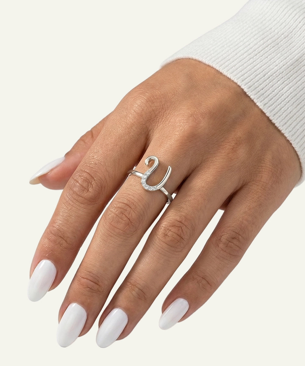 Silver ring on a hand with white nail polish against a light background