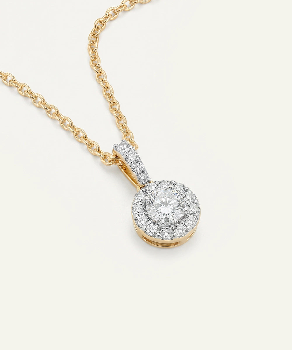 Gold necklace with a diamond pendant on a light gray background