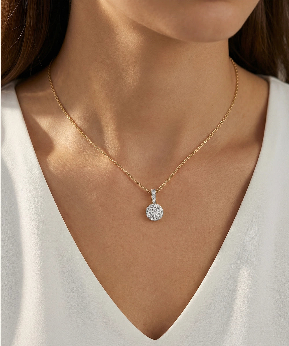 Silver necklace with a diamond pendant worn by a person in a white top.