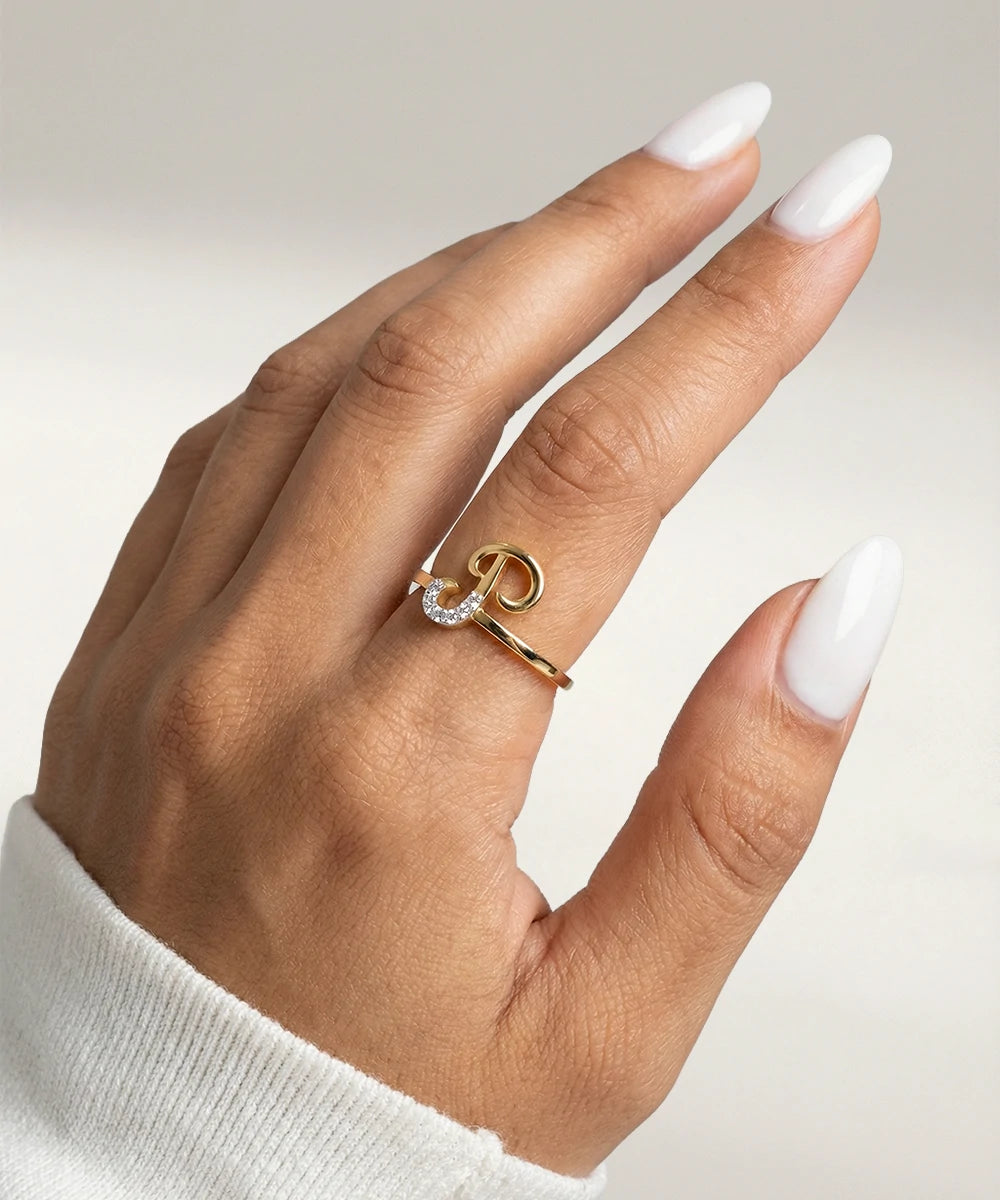 Hand wearing a gold ring with a diamond on a neutral background