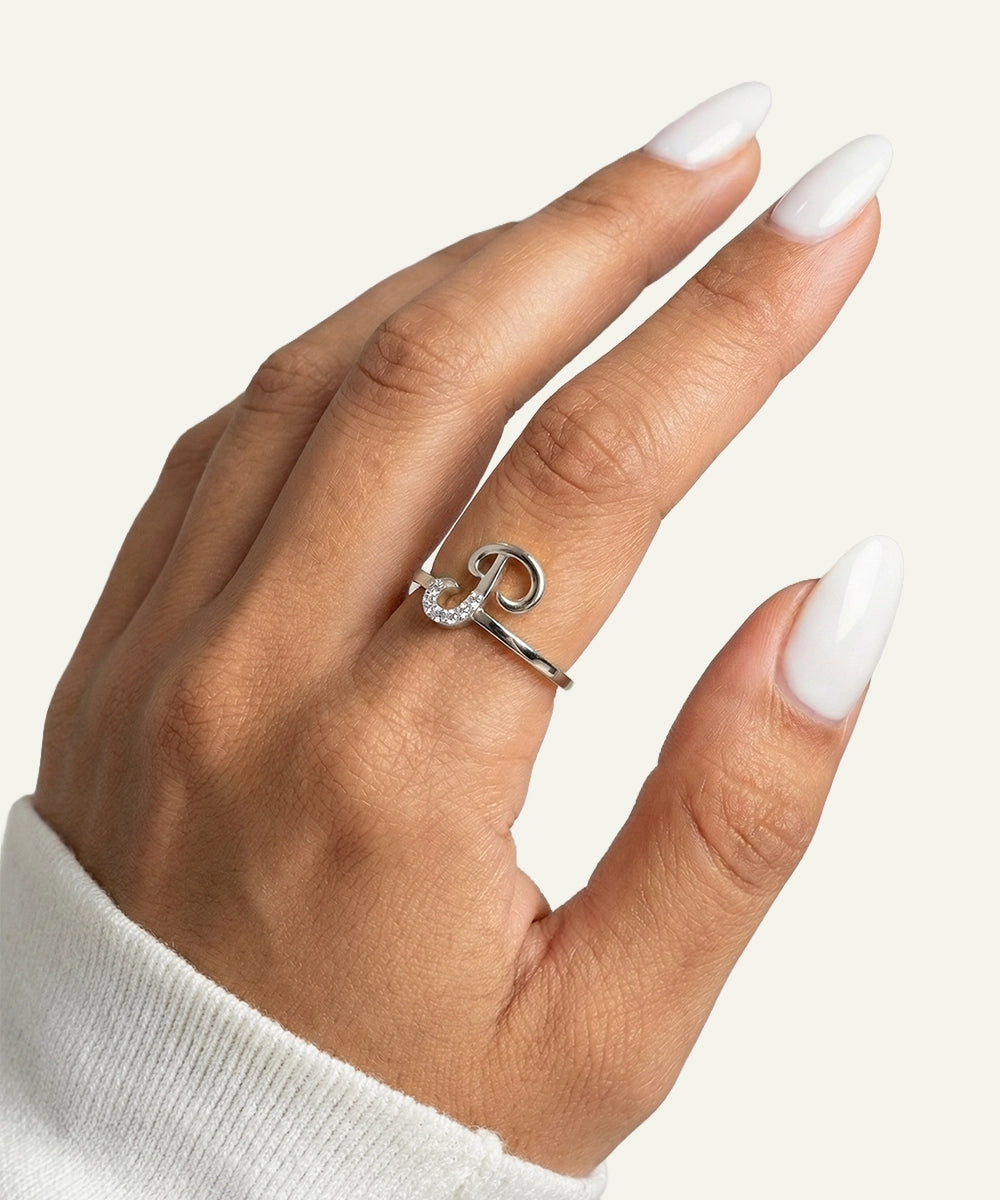 Hand wearing a silver ring with a diamond on a light background