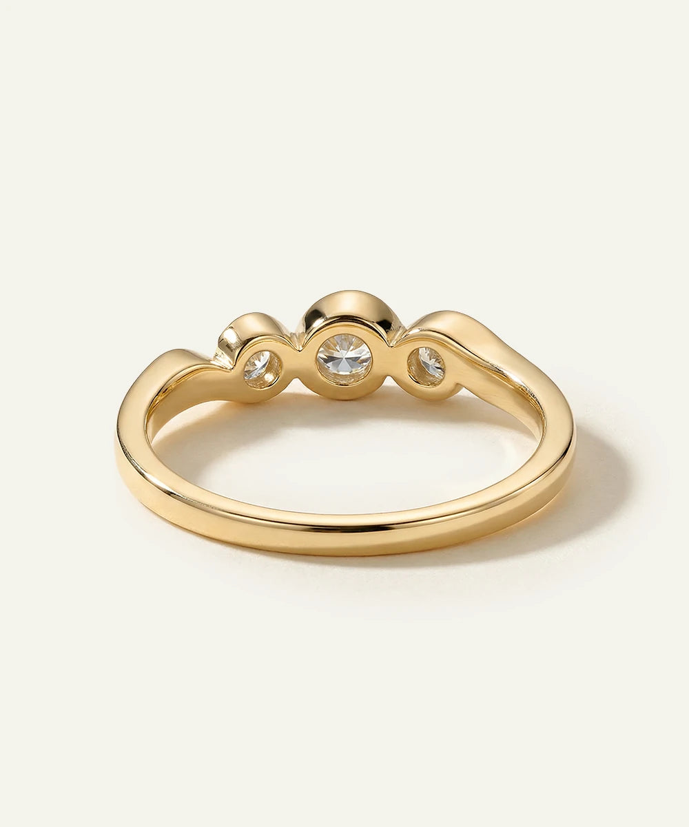 Gold ring with three small diamonds on a light beige background