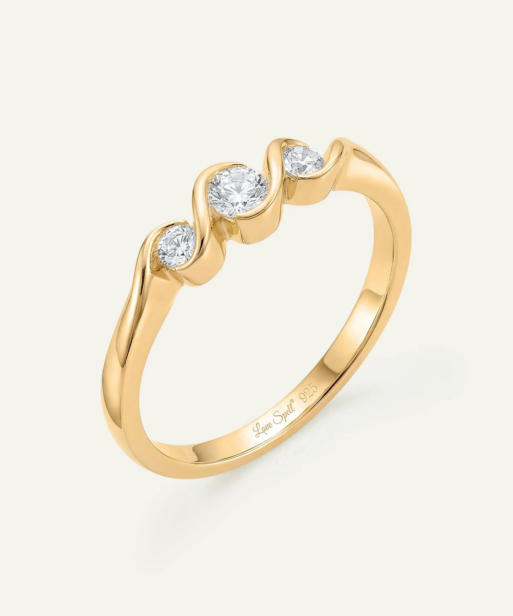 Gold ring with three diamonds on a light beige background