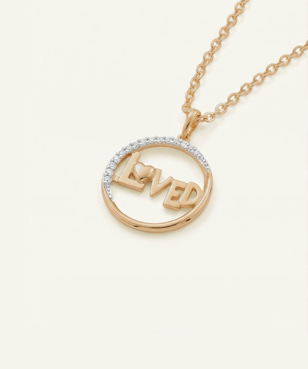 Gold necklace with 'LOVED' pendant on a white background