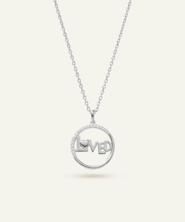 Silver necklace with a pendant that reads 'LOVED' on a white background