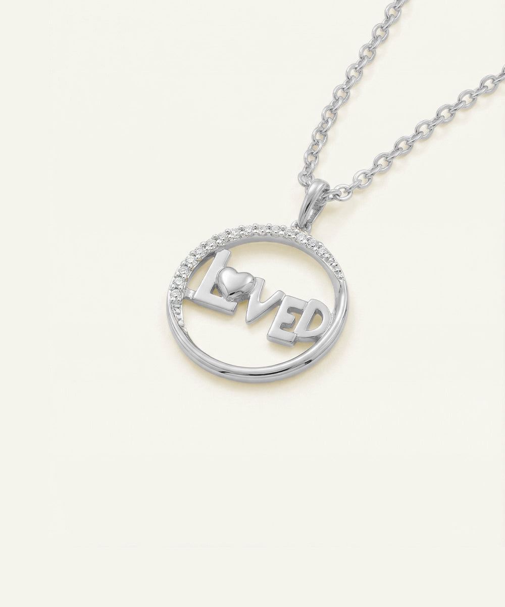 Silver necklace with 'LOVE' pendant on a light beige background