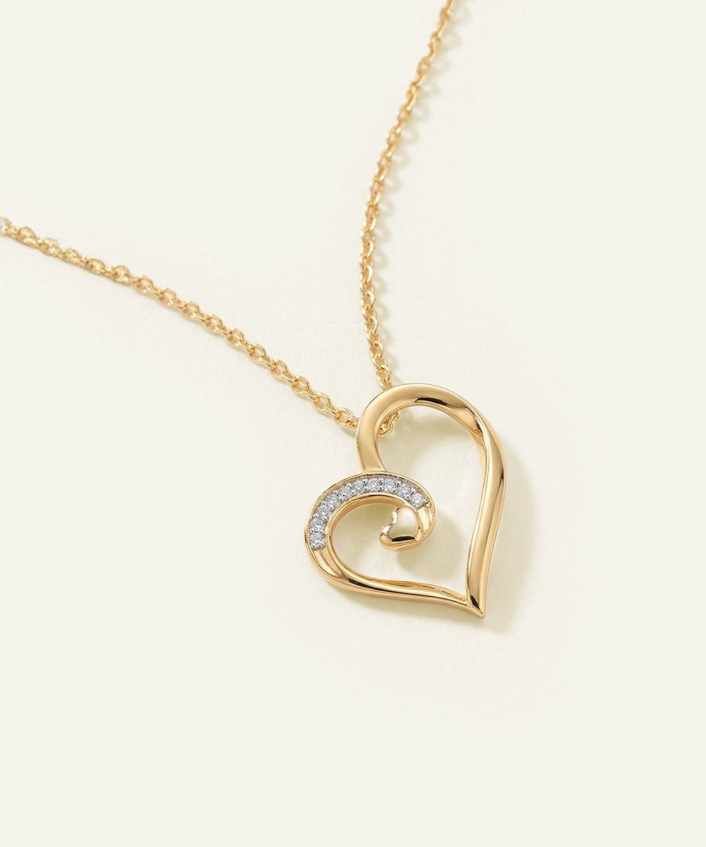 Gold heart-shaped necklace with a chain on a light beige background