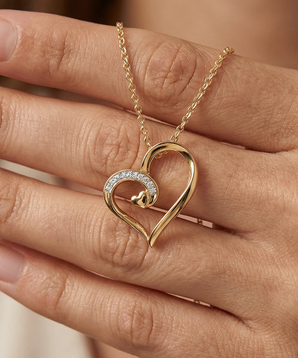 Gold heart-shaped necklace with diamond details on a hand
