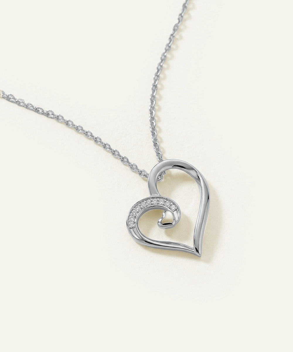 Silver heart-shaped pendant necklace on a light beige background