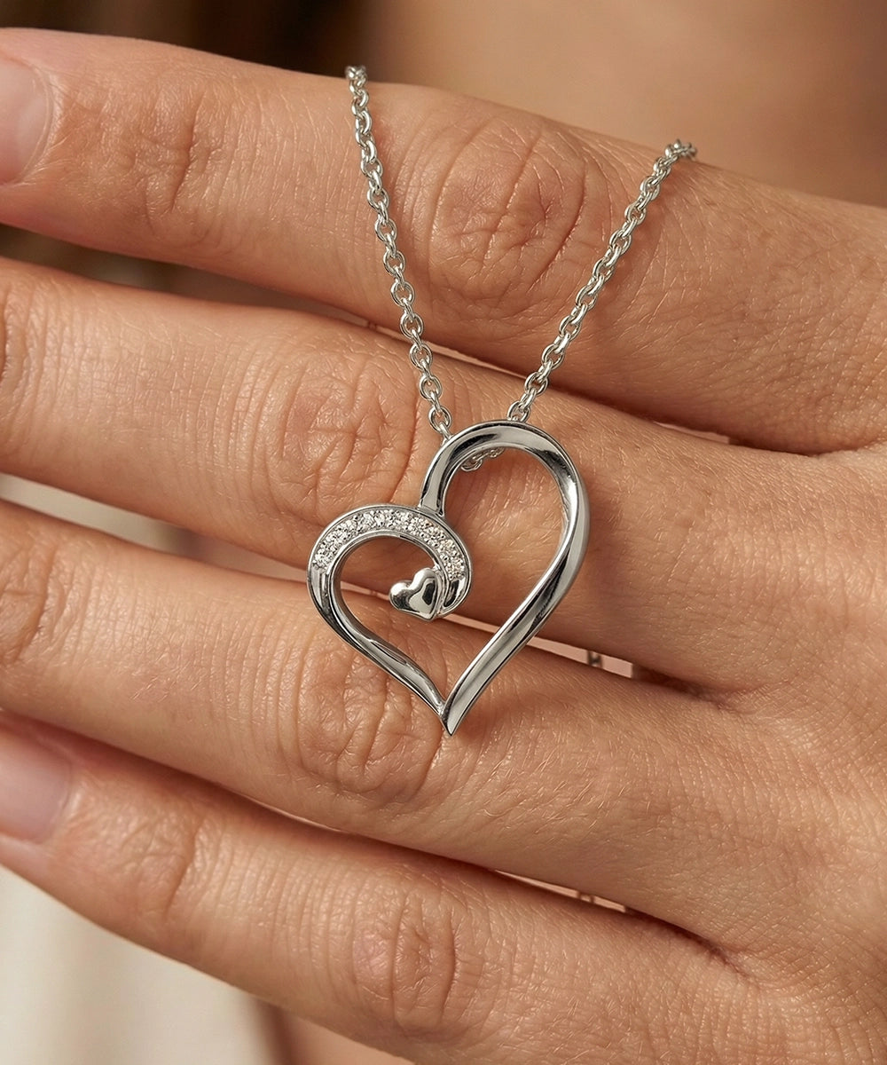Silver heart-shaped necklace on a hand