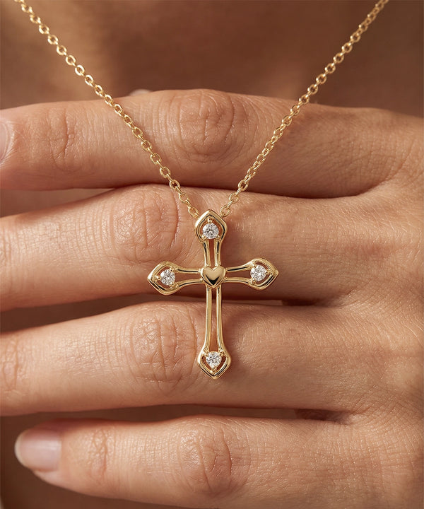 Gold cross necklace with diamonds on a hand