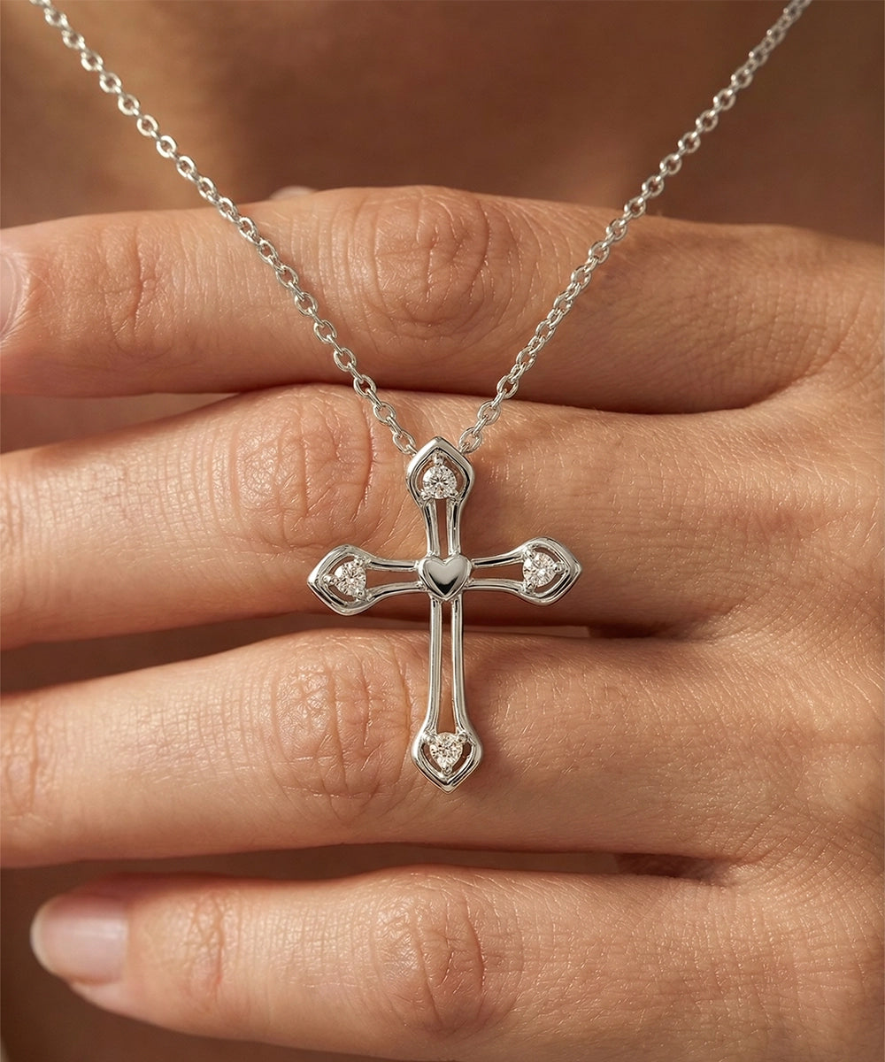 Silver cross necklace with heart details on a hand