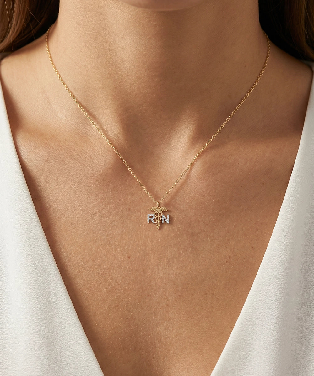 Gold necklace with a pendant on a person wearing a white top