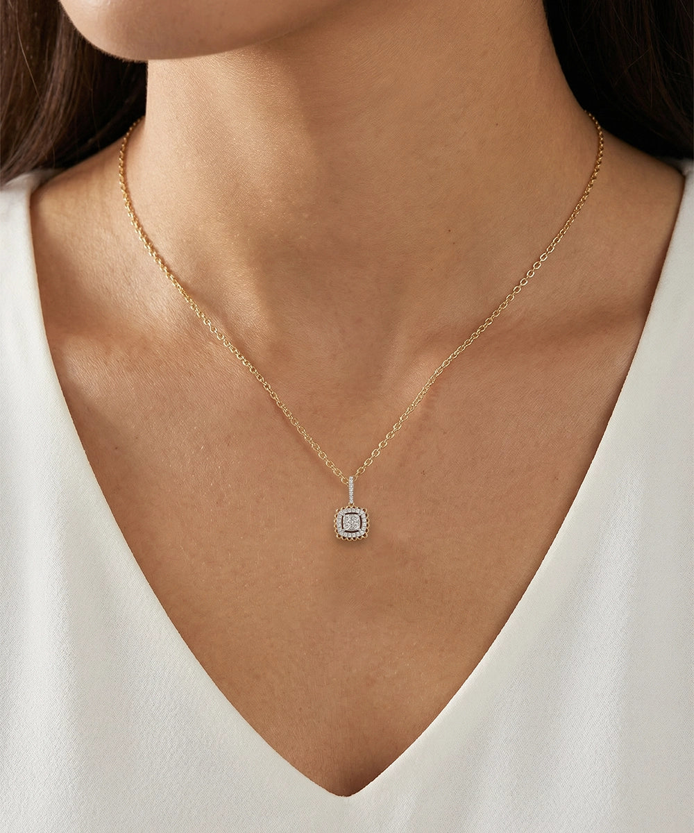 Gold necklace with a pendant worn by a person in a white top