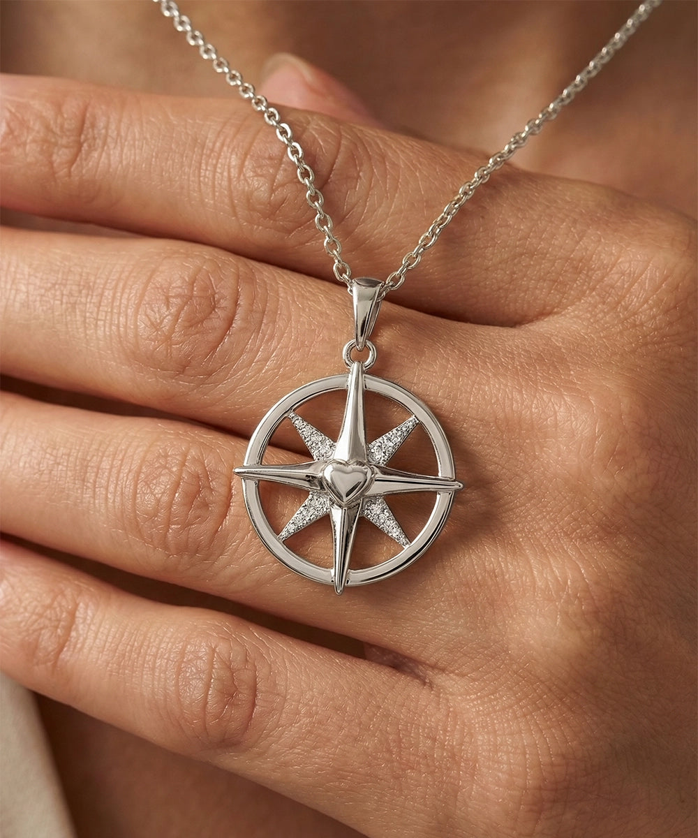 Silver compass pendant necklace on a hand