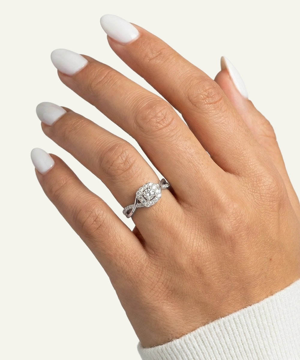 Hand wearing a diamond ring with a plain background