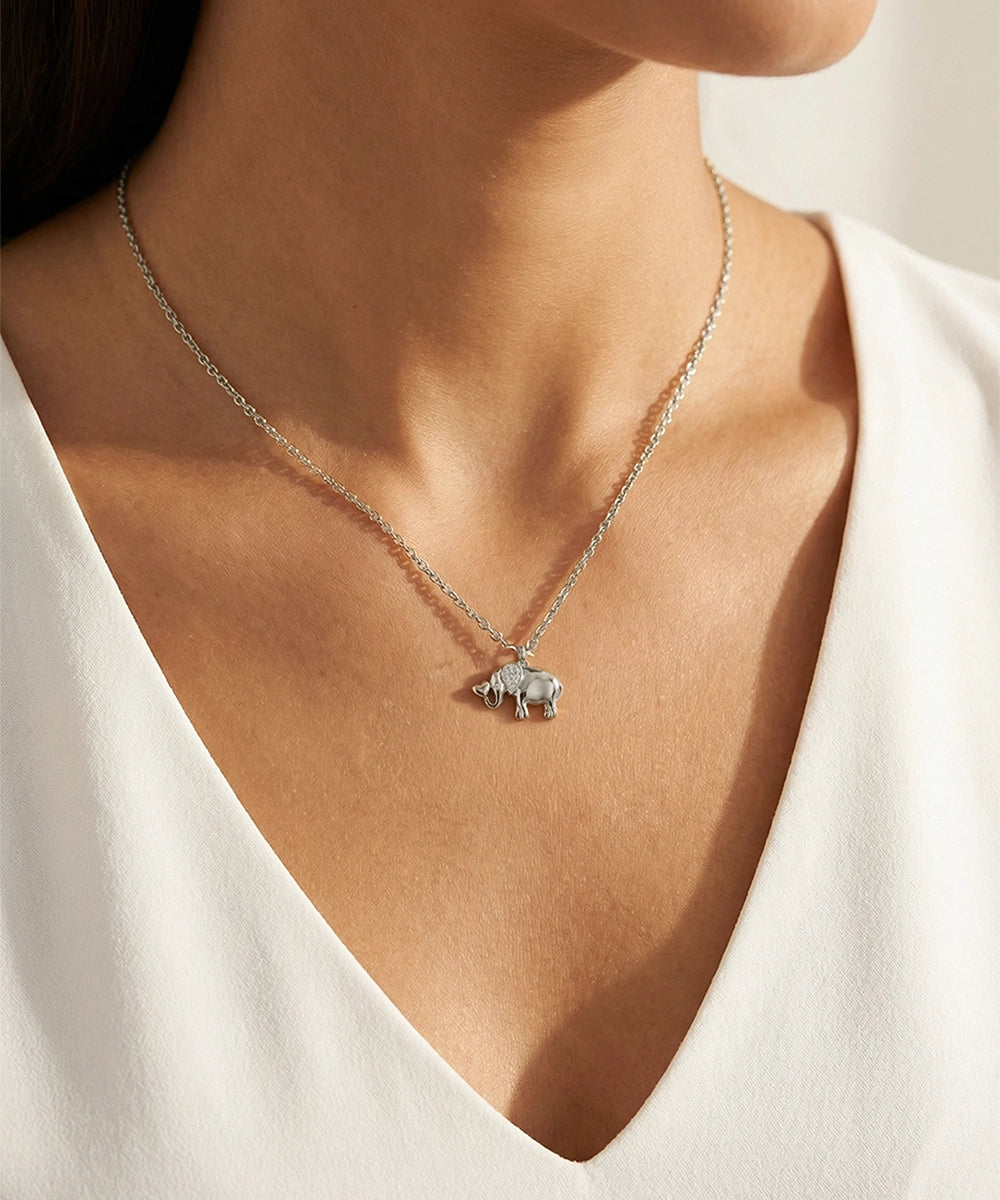 Necklace with a small elephant pendant worn by a person in a white top.