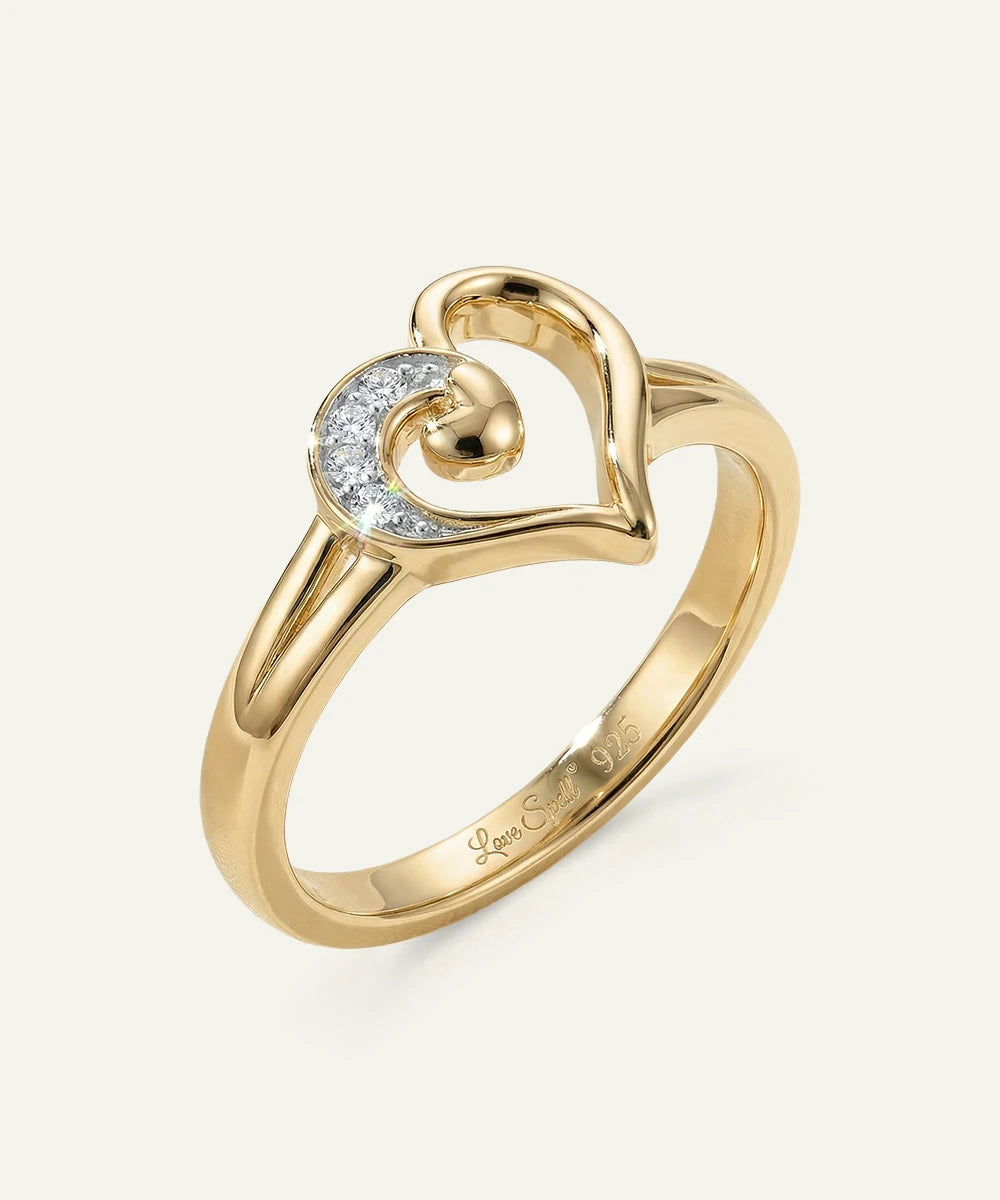 Gold ring with heart design and embedded diamonds on a white background