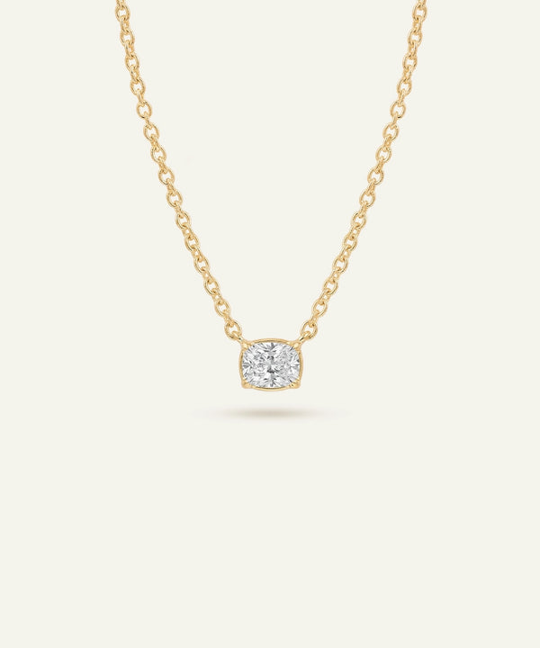 Gold necklace with a diamond pendant on a light beige background