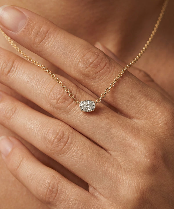 Gold necklace with a diamond pendant on a hand