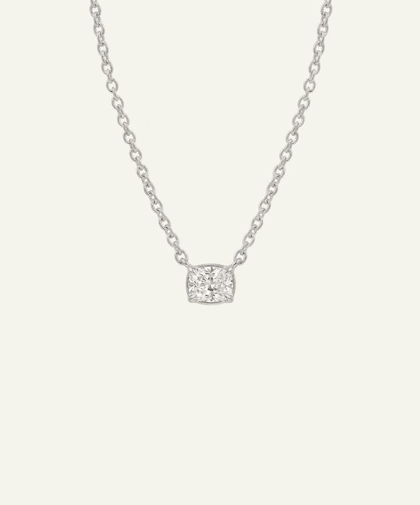 Silver necklace with a square pendant on a light gray background