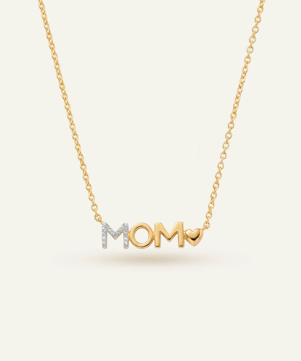 Gold necklace with 'MOM' pendant on a light beige background