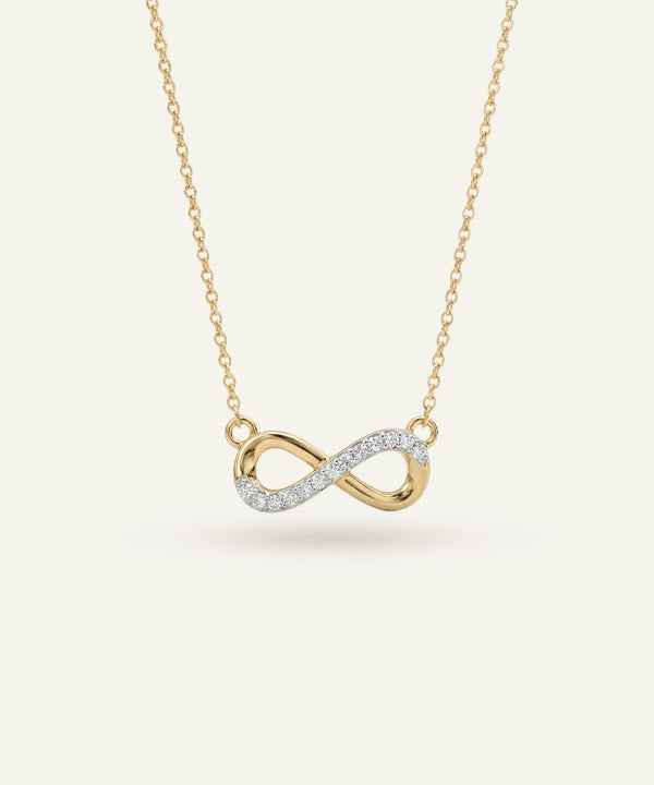 Gold infinity necklace with diamonds on a light beige background
