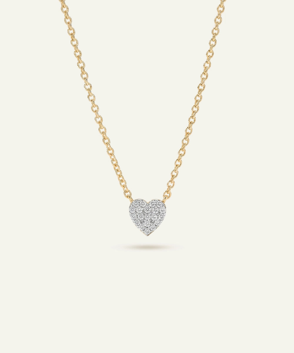Heart-shaped diamond pendant on a gold chain against a white background