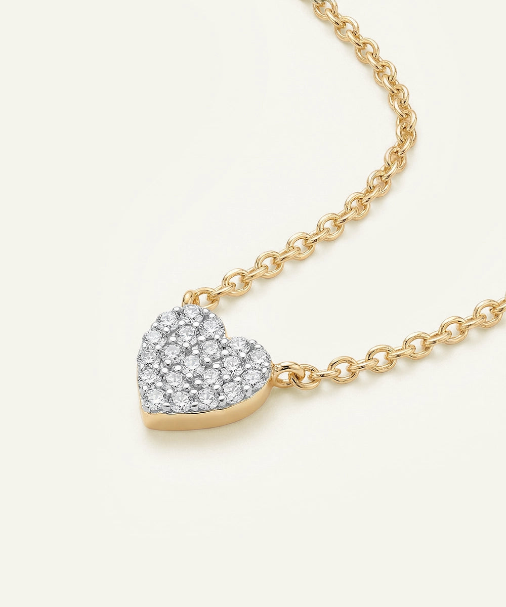 Gold necklace with a heart-shaped diamond pendant on a white background