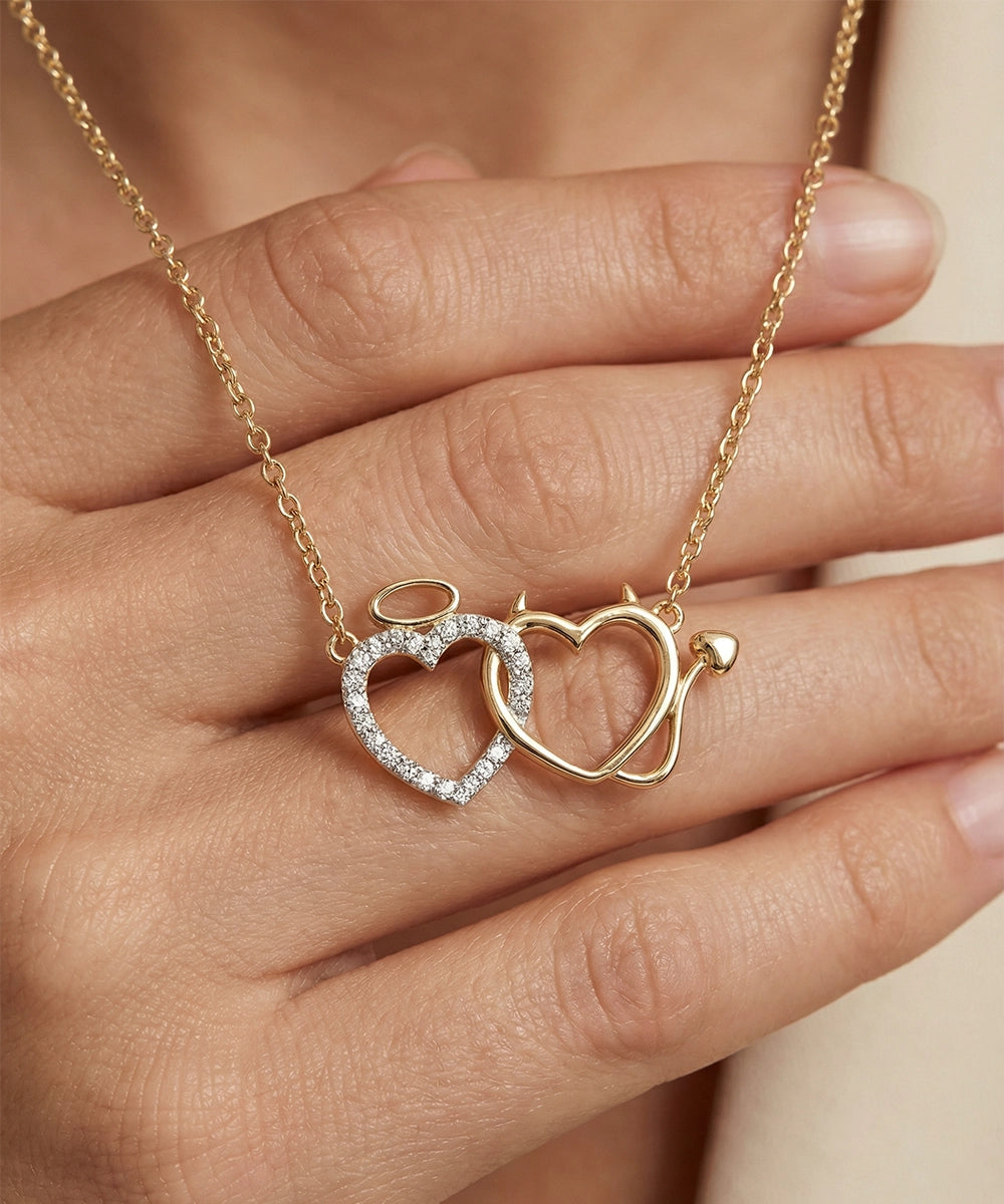 Gold necklace with interlocking heart pendants held by a hand