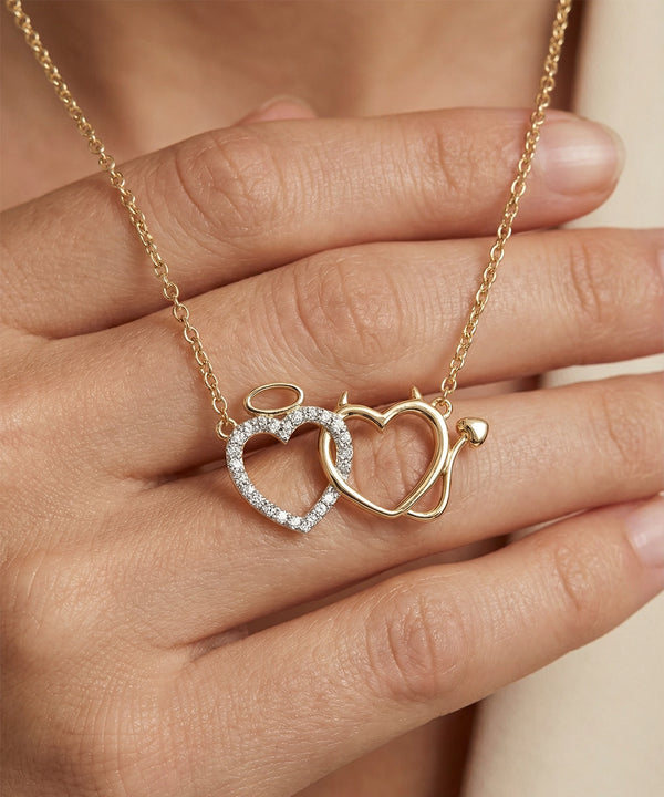 Gold necklace with interlocking heart pendants held by a hand