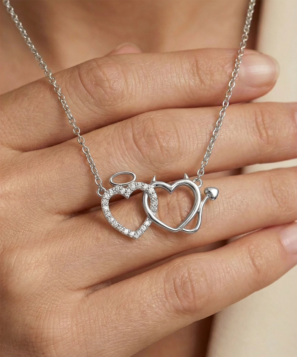 Silver necklace with interlocking heart pendants held by a hand