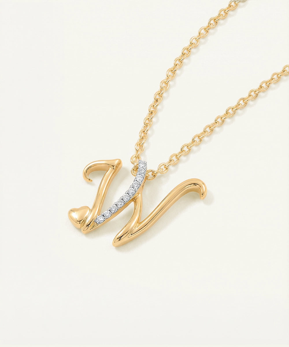 Gold necklace with a 'W' pendant on a light beige background