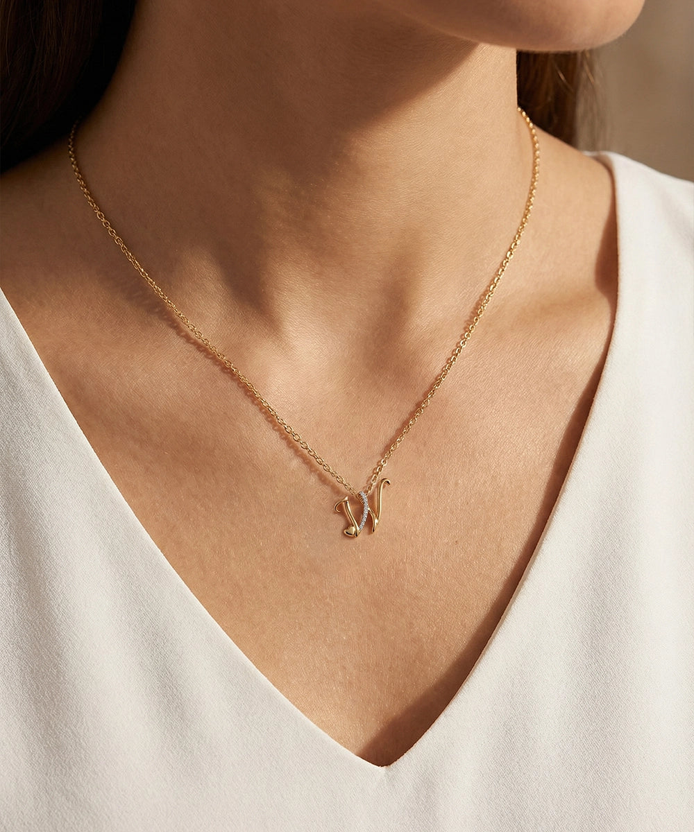 Gold necklace with a pendant on a person wearing a white top.
