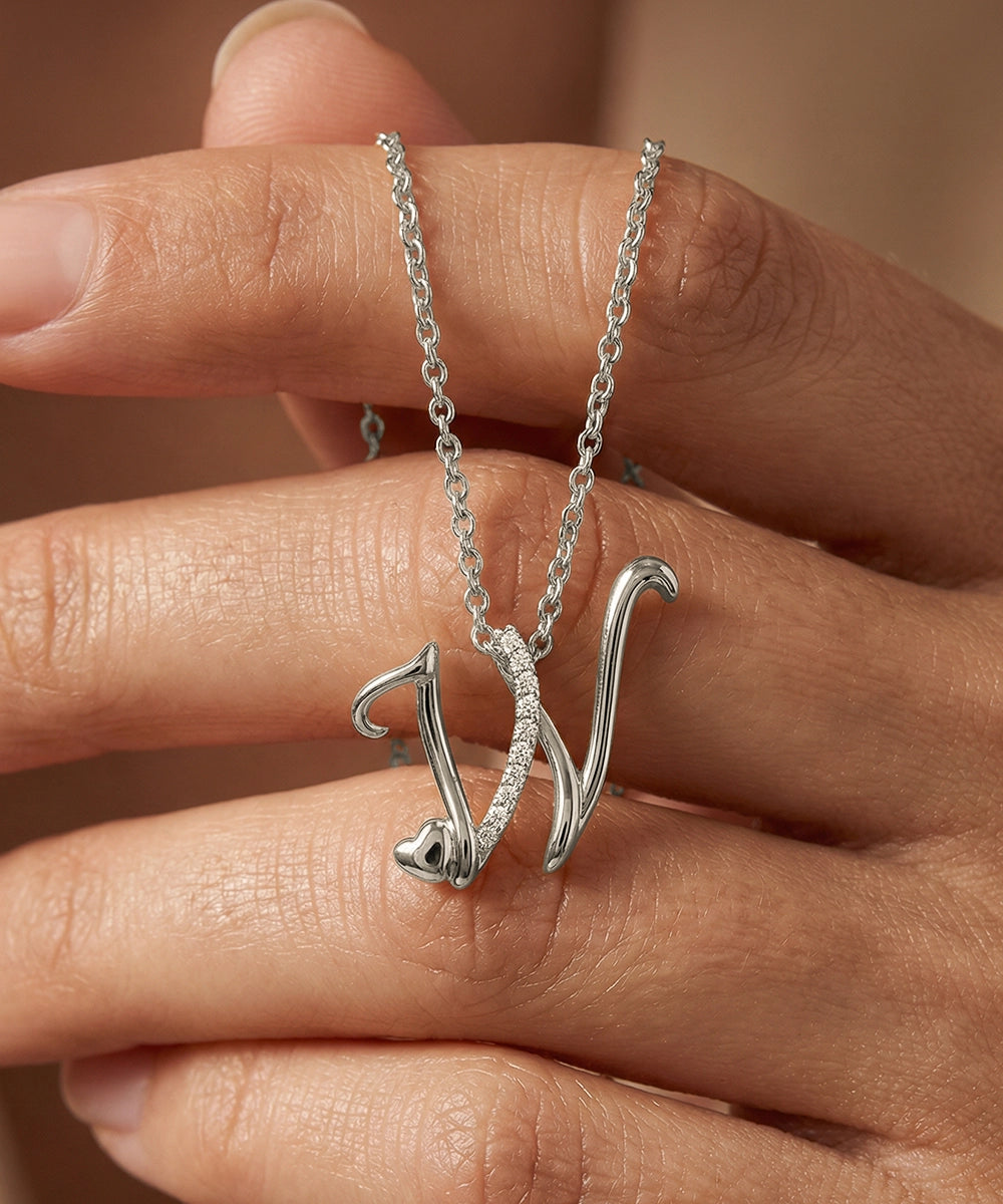 Silver necklace with a unique pendant held between fingers against a neutral background