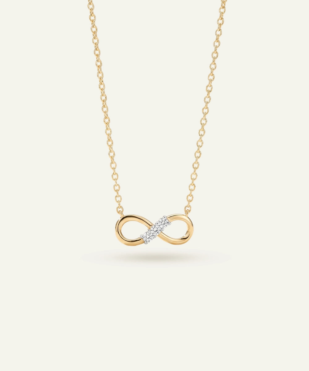 Gold infinity necklace with a diamond on a white background