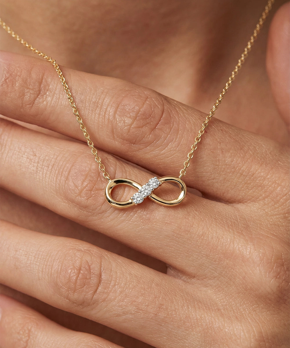 Gold necklace with an infinity pendant on a hand