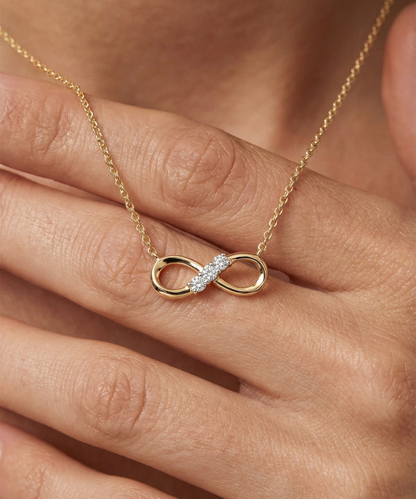 Gold necklace with an infinity pendant on a hand