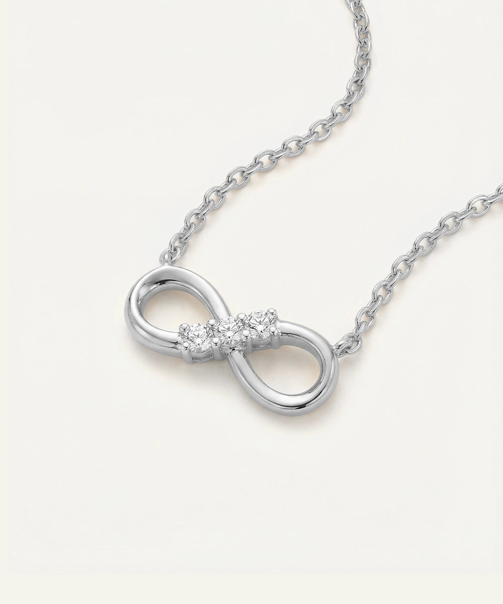 Silver infinity necklace with diamonds on a white background