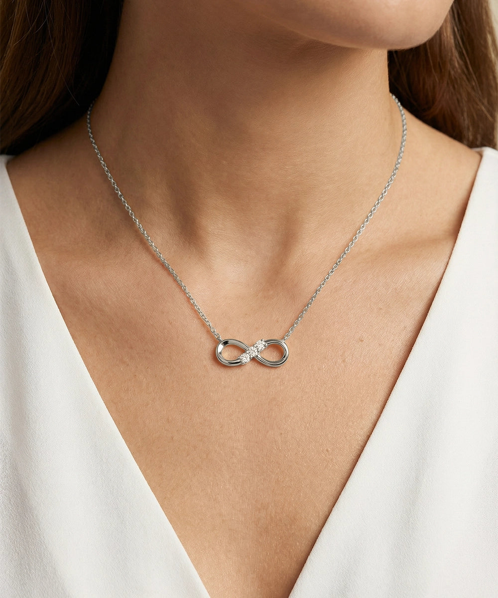 Silver necklace with a unique pendant worn by a person in a white outfit.